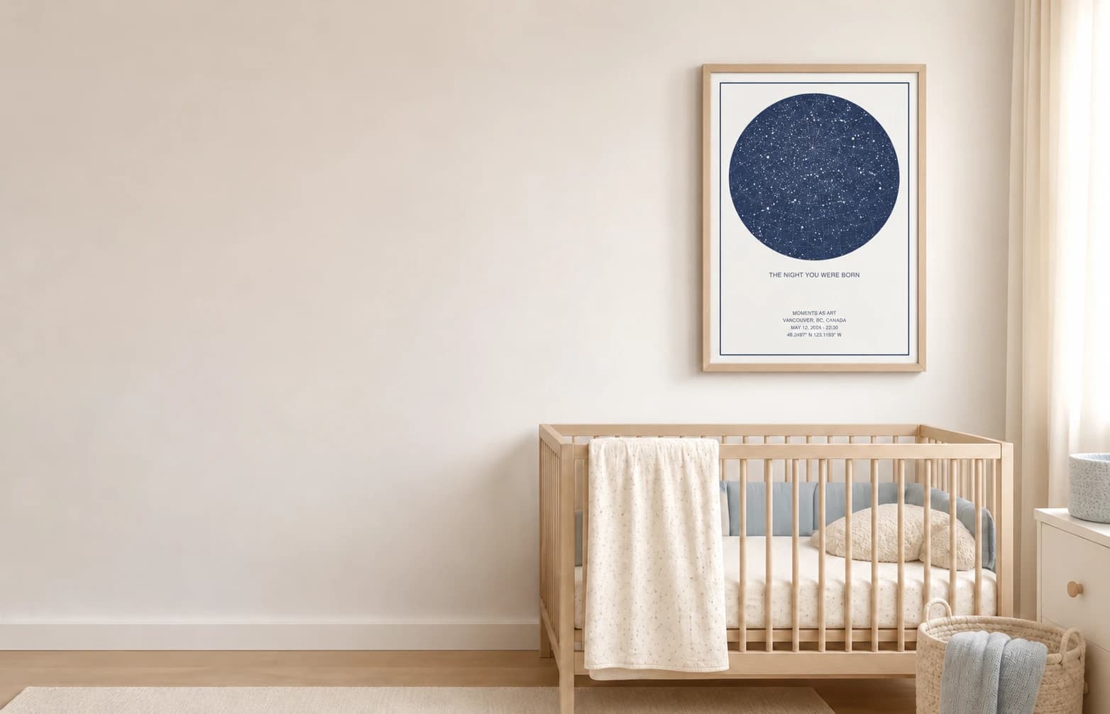 A framed navy star map titled The Night You Were Born hanging above a wooden crib in a nursery