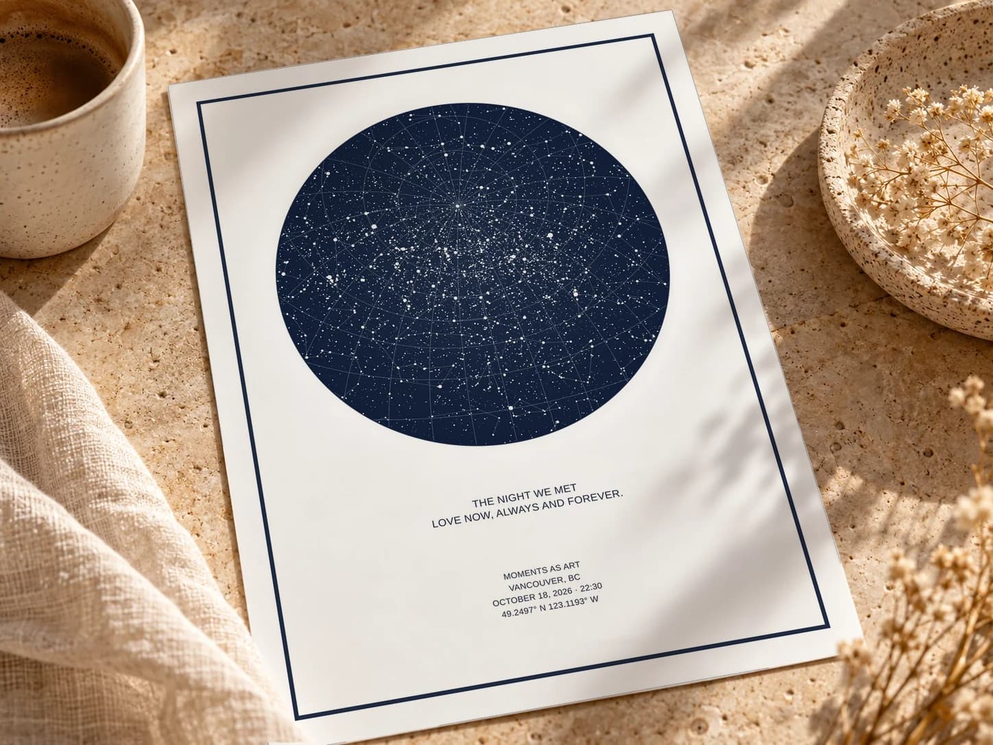 A navy star map of Vancouver titled The Night We Met printed on white matte paper, lying on a stone table beside a coffee cup